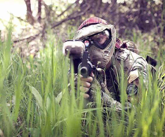 buck playing paintball hiding in grass and aiming