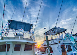 sun setting behind two fishing boats