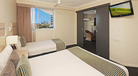 one single and one double bed with television in Gold Coast apartment