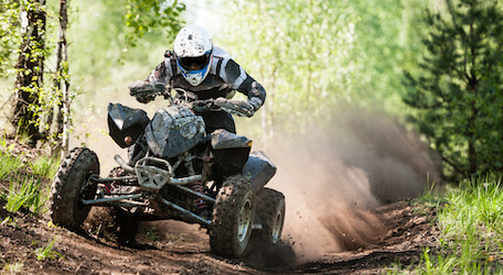 buck riding dirt bike along forrest track