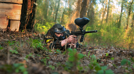 buck lying on ground shooting paintball gun