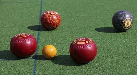 5 lawn bowls sitting on grass