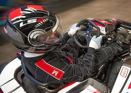 man in helmet driving black and white race car