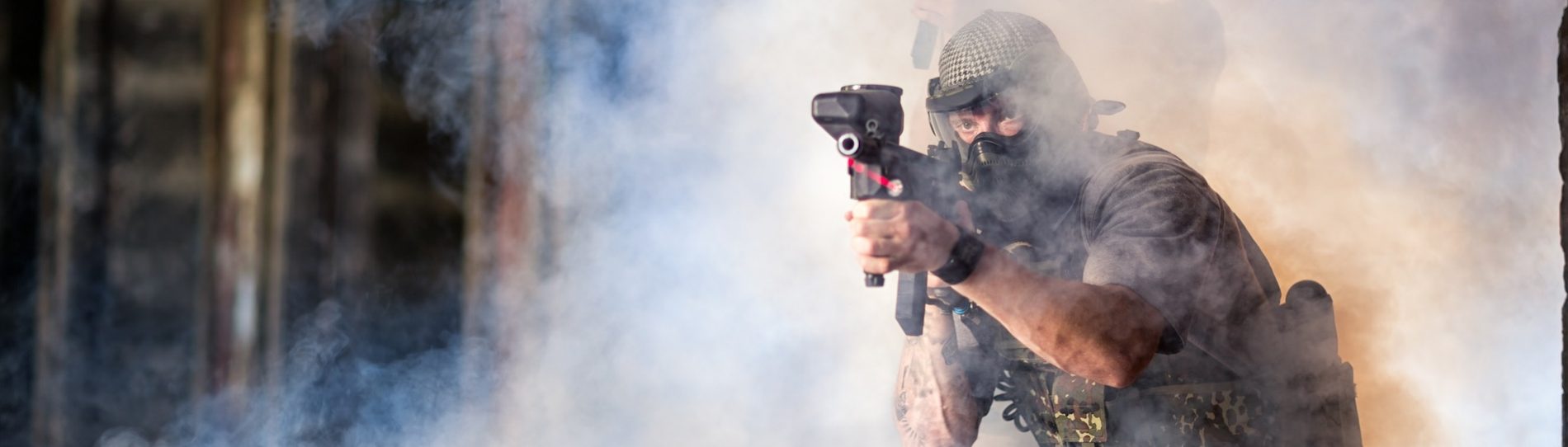 army man shooting paintball gun surrounded by smoke
