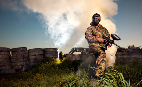 buck playing paintball with tires and smoke in the background