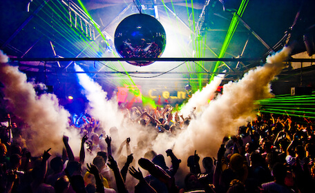 crowd of people partying at nightclub with disco ball and smoke