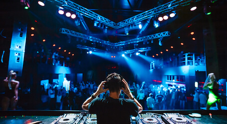 dj in nightclub with decks and led lights