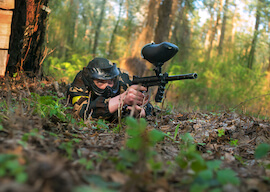 buck lying in the woods with a paintball gun