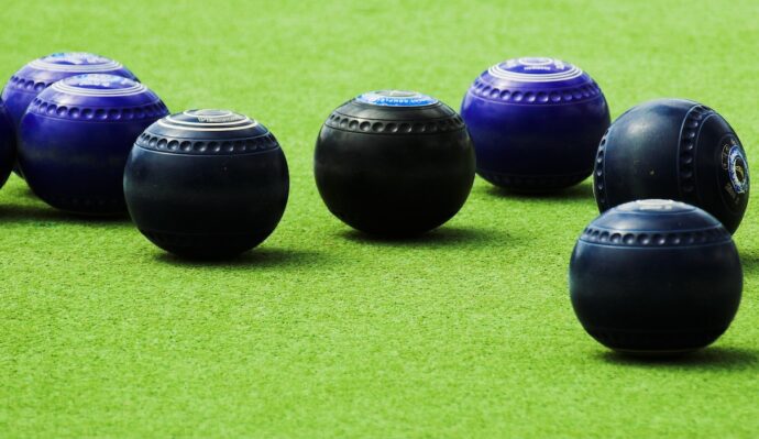 mutiple bowls sit on a lawn ready to play lawn bowls