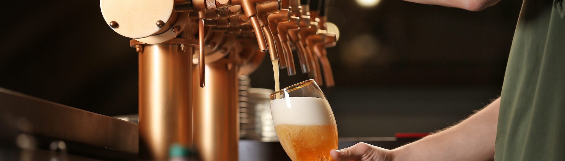 man is pouring beer from beer tap