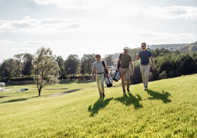 group of men are walking across a golf course