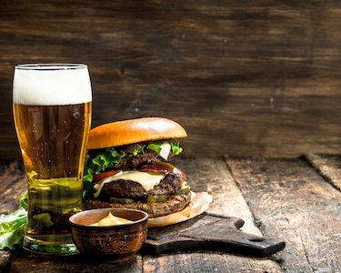 big burger and beer on wooden palate