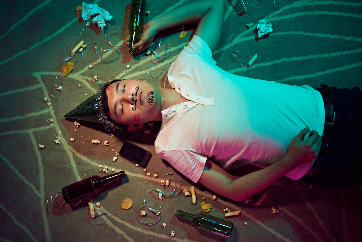 man is lying on the ground covered in party streamers after a big night celebrating