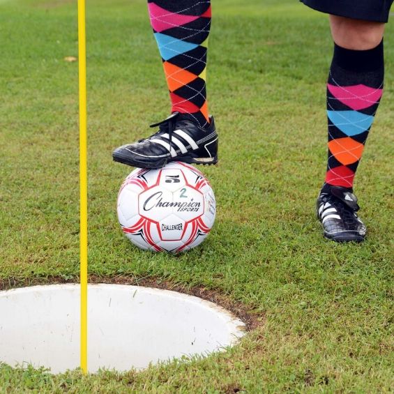 guy holding soccer ball with his foot near the hole